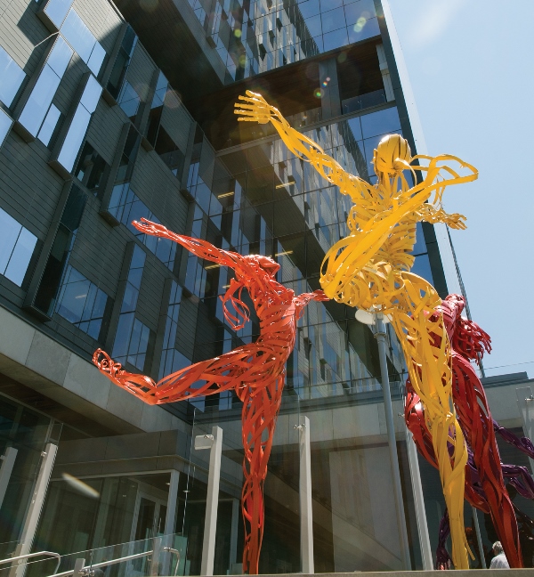 Image of sculptures in bright colours depicting life-sized human figures dancing.