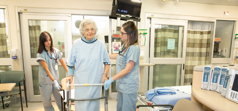 elderly patient with a walker with 2 nurses with her
